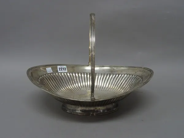 A George III silver cake or fruit basket, of oval form with partly fluted decoration, within a reeded border, the swingover handle and the oval foot w