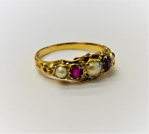 A gold, ruby and cultured pearl ring, mounted with two cushion shaped rubies, alternating with three cultured pearls, the mount with scroll decoration