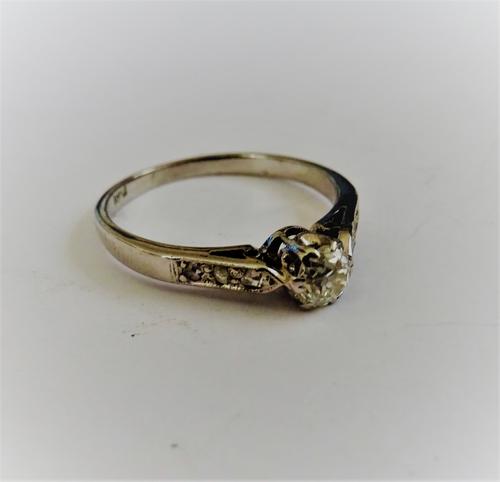 A white gold and diamond set ring, mounted with the principal cushion shaped diamond between diamond three stone shoulders, detailed 18 CT, ring size