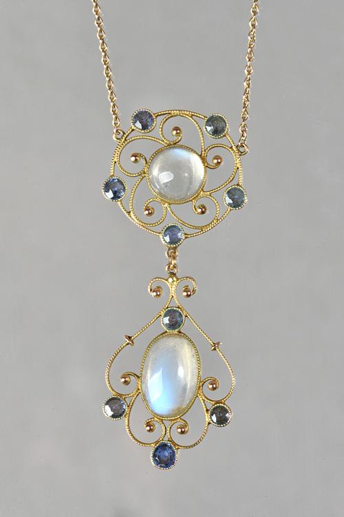 A gold, sapphire and moonstone pendant necklace, mounted with an oval and a circular moonstone and otherwise set with circular cut sapphires, in a pie