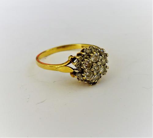 An 18ct gold and diamond cluster ring, claw set with the seven principal circular cut diamonds to the centre, in a surround of smaller circular cut di