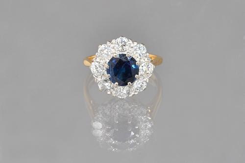 An 18ct gold, sapphire and diamond cluster ring, claw set with the circular cut sapphire at the centre, in a surround of eight circular cut diamonds,