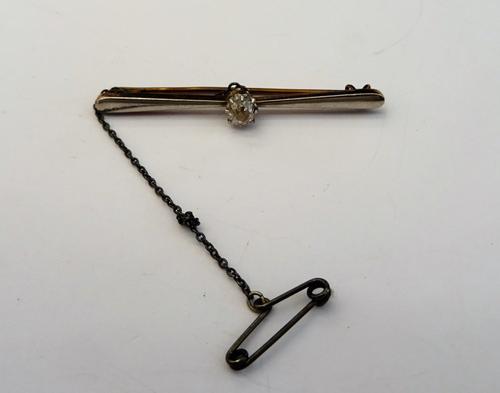 A diamond set single stone bar brooch, claw set with a cushion shaped diamond fitted with a safety chain, with a case.