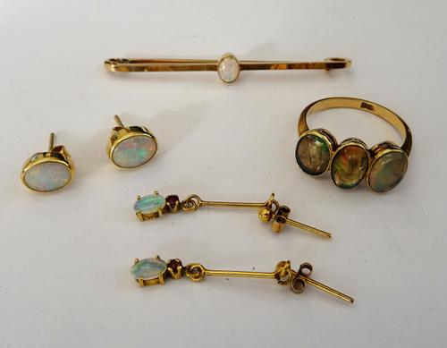 A gold bar brooch, mounted with an oval opal, detailed 15 CT, a gold and water opal three stone ring, a pair of opal single stone earstuds, each mount