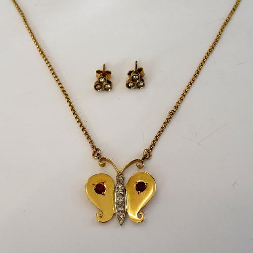 A gold, diamond and ruby set pendant necklace, the front designed as a butterfly, mounted to the centre with a row of six circular cut diamonds and ot