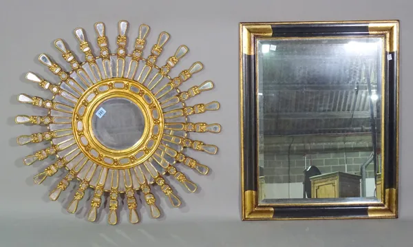 A 20th century gilt wall mirror of circular form, with sectional glazed star burst border and an ebonised and gilt rectangular mirror, (2).   A7