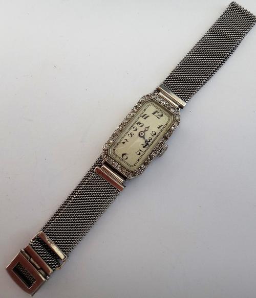 A platinum cased and diamond set lady's cut cornered rectangular cased dress wristwatch, with an unsigned jewelled movement, the dial with black Arabi