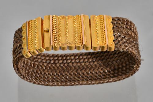 A Victorian gold mounted woven hairwork bracelet, the snap clasp with applied beaded decoration, with the original case. Illustrated.
