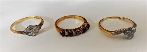 A gold and diamond ring, mounted with the three principal cushion shaped diamonds to the centre, between diamond set shoulders, in a twistover design,