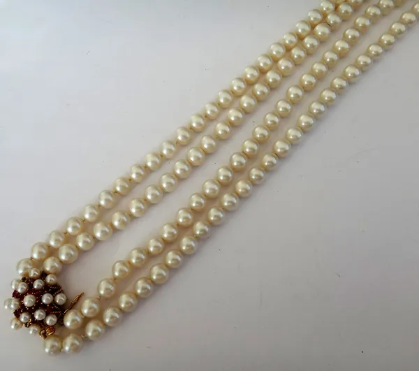 A two row necklace of uniform cultured pearls, on a gold, cultured pearl and ruby set clasp, detailed 14 K..