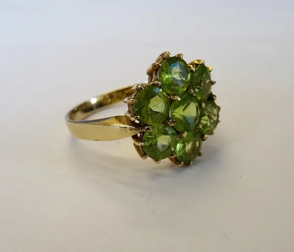 A 9ct gold and peridot seven stone cluster ring, mounted with circular cut peridots, ring size P, with a box.