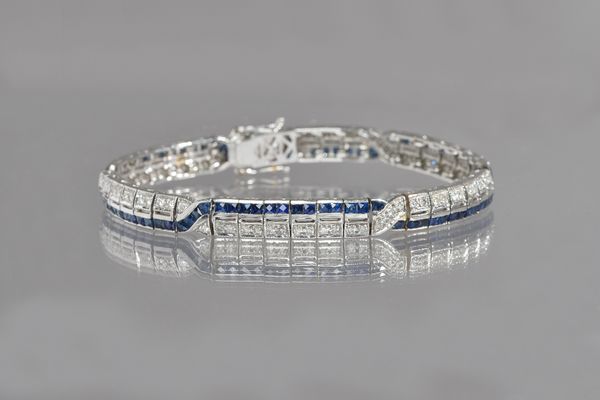 A white gold, sapphire and diamond bracelet, in an Art Deco inspired design, formed as two entwined rows of calibre cut sapphires and eighty-eight cir