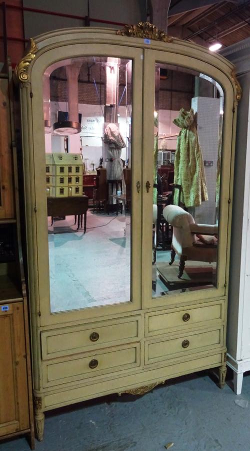 A 20th century French green painted arch top armoire, with bevelled mirrored doors and four drawers to base on fluted tapering supports, 120cm wide x