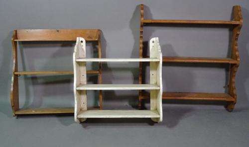 A early 20th century white painted three tier wall shelf 62cm wide x 63cm high and two other three tier pine wall shelves, the larger 70cm wide x 90cm