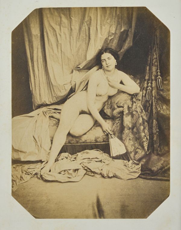 AUGUSTE BELLOC  (1800 - 1867)  Reclining female nude on chaise longue, ca, 1855.  salt print, mounted on card, 20.7cm x 15.5cm, unframed.