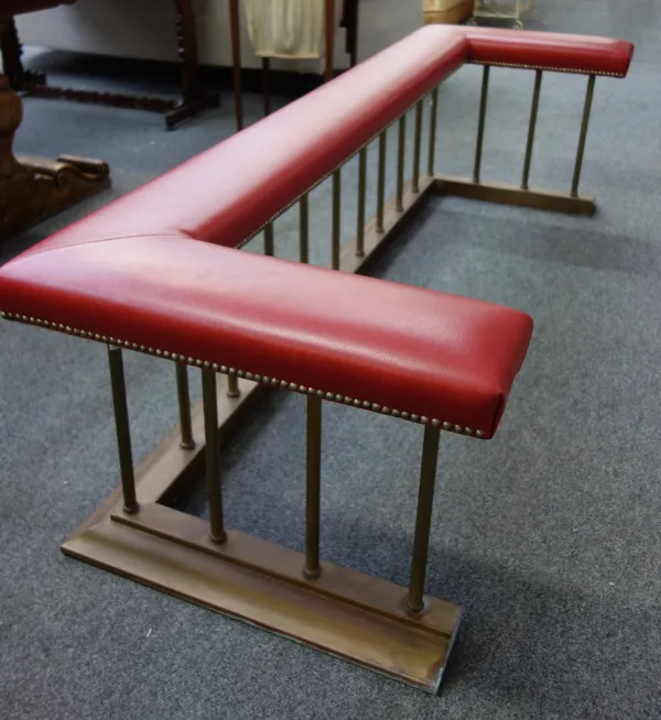 A Victorian style gilt metal club fender, modern, with red leather upholstery, over a pillared rail and stepped plinth, 190cm wide.