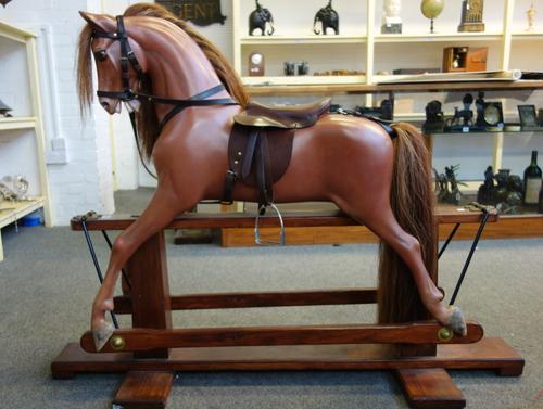 A Haddon composite rocking horse, after a model by F.H. Ayres, fibreglass painted body with leather saddle and tack, on a wood and wrought iron swing