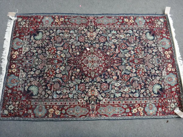 An Indian part silk rug, the dark blue field with a central lobed medallion, within profusely scrolling floral and bird decoration, claret red border,