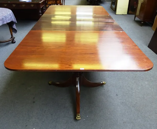 A George III style mahogany extending twin pedestal dining table, each pedestal with turned column and three downswept supports, two extra leaves, 137