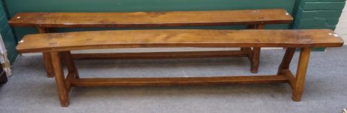 A pair of 19th century French oak benches, on splayed staked supports united by stretcher, 219cm wide x 46cm high x 19cm across at the seat. (2)