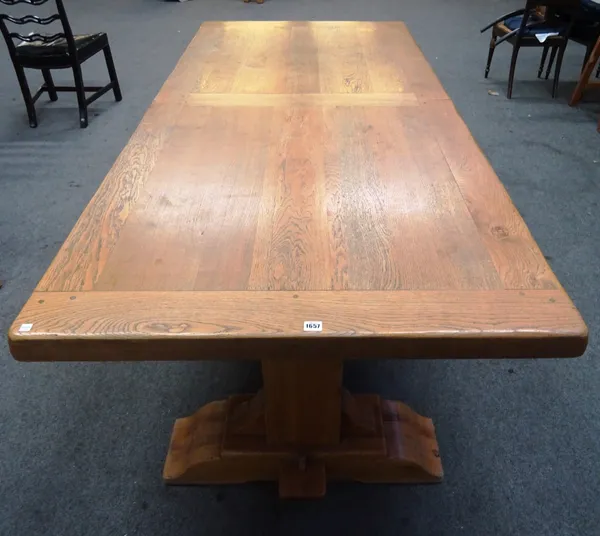 A 20th century oak extending dining table of 17th century design, the rectangular top on canted trestle ends united by stretcher, to include two extra