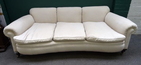 A late 19th century cream upholstered sofa, with concave seat and roll over arms, on turned supports, 240cm wide x 77cm high.