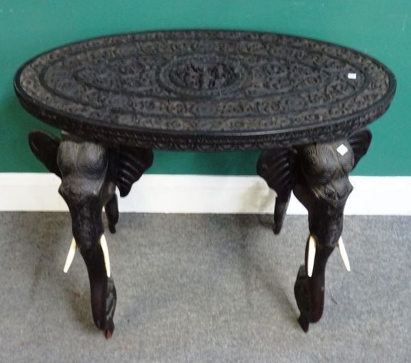 A 19th century Anglo-Indian Coromandel Coast carved ebony oval occasional table, on four elephant head carved supports, 92cm wide x 68cm high x 54cm d