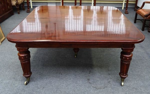 A large Victorian mahogany extending dining table, the rounded rectangular top on five turned tapering fluted supports and heavy brass castors, to inc