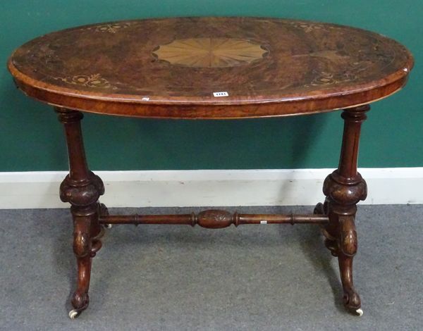 A Victorian walnut centre table, the marquetry inlaid oval top on a pair of turned columns and four downswept supports, 105cm wide x 60cm deep x 74cm