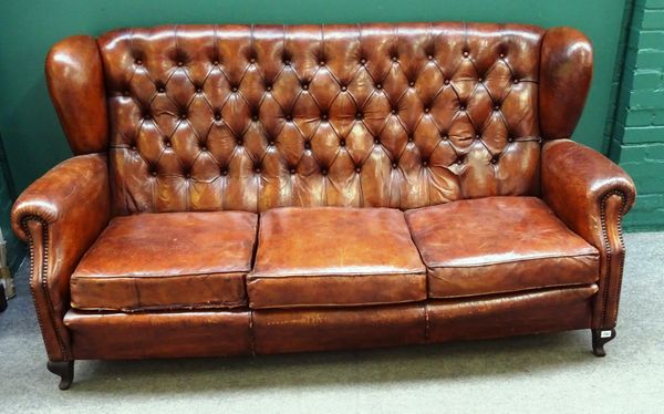 An early 20th century tan leather button upholstered wingback sofa, on squat cabriole supports, 188cm wide x 95cm high.