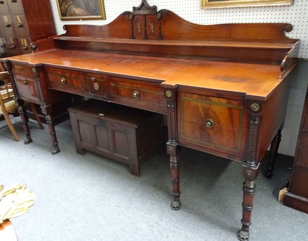 A massive George IV brass inlaid mahogany sideboard, the scroll ledge back over drop front central drawer, flanked by pair of cupboards divided by spl