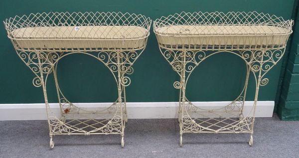 A pair of Edwardian cream painted oval wirework plant stands, with lattice undertier, 90cm wide x 88cm high, (2).