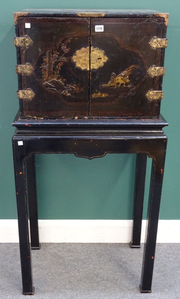 An 18th century Chinese export black lacquer chinoiserie decorated cabinet on later stand, the pair of doors enclosing eight various drawers, 65cm wid