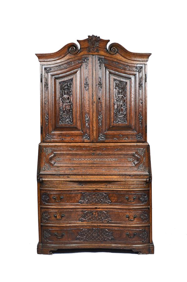 An 18th century Walloon carved oak bureau cabinet, probably Liège, the scroll cornice over a pair of doors, stepped and welled interior and three serp