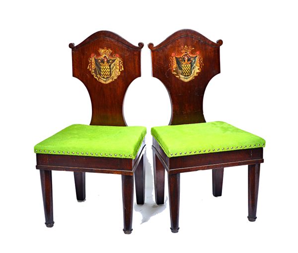 A pair of early 19th century North European mahogany framed hall chairs, the shield backs with polychrome painted armorial decoration, on turned suppo