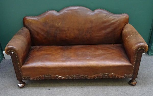 A mid-20th century leather upholstered sofa, with shaped back and carved oak frame on compressed bun feet, 170cm wide x 86cm high.