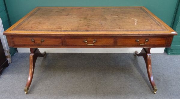 A George III style mahogany centre writing table, the leather inset rectangular top with three frieze drawers and a dummy opposing, on trestle end sta