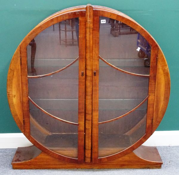 A 1930s walnut circular two door display cabinet on swept pedestal base, 120cm wide x 129cm high.