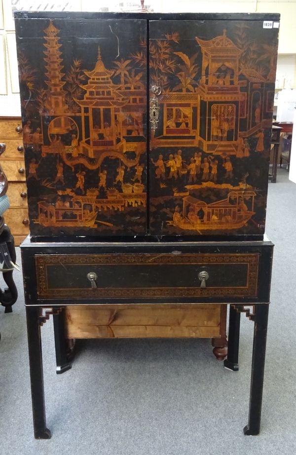 A mid-18th century style black lacquer chinoiserie decorated cabinet on stand, the pair of doors enclosing fourteen drawers above a single drawer base