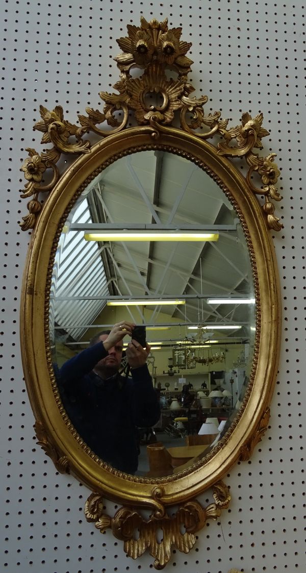 A pair of mid-19th century style gilt framed oval wall mirrors, with pierced and carved floral chased frames, 62cm wide x 125cm high, (2).