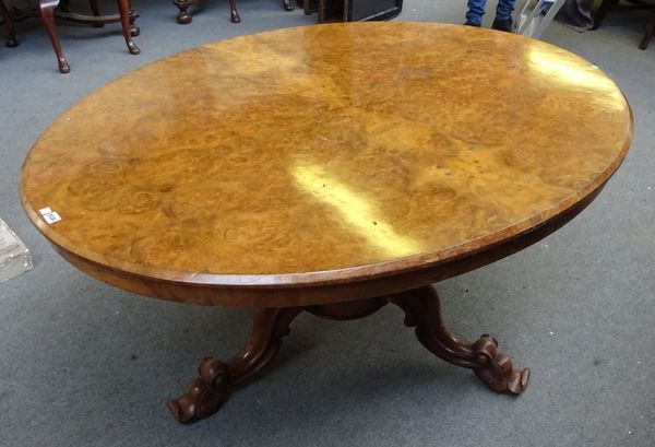 A Victorian figured walnut centre table, the oval snap top on a carved tripod base, 150cm wide x 116cm deep.