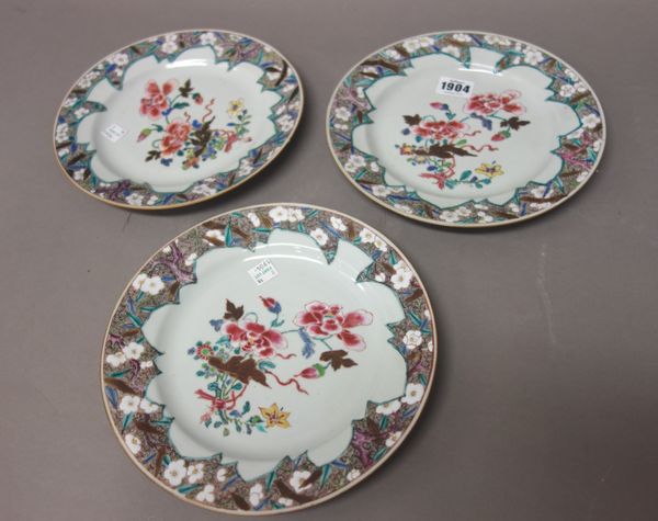 Three Chinese famille-rose plates, early Qianlong, each painted with a central group of flowers inside a brown whorl border painted with flowering pru