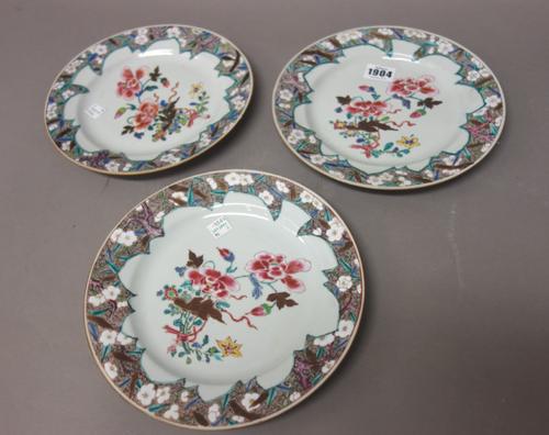 Three Chinese famille-rose plates, early Qianlong, each painted with a central group of flowers inside a brown whorl border painted with flowering pru