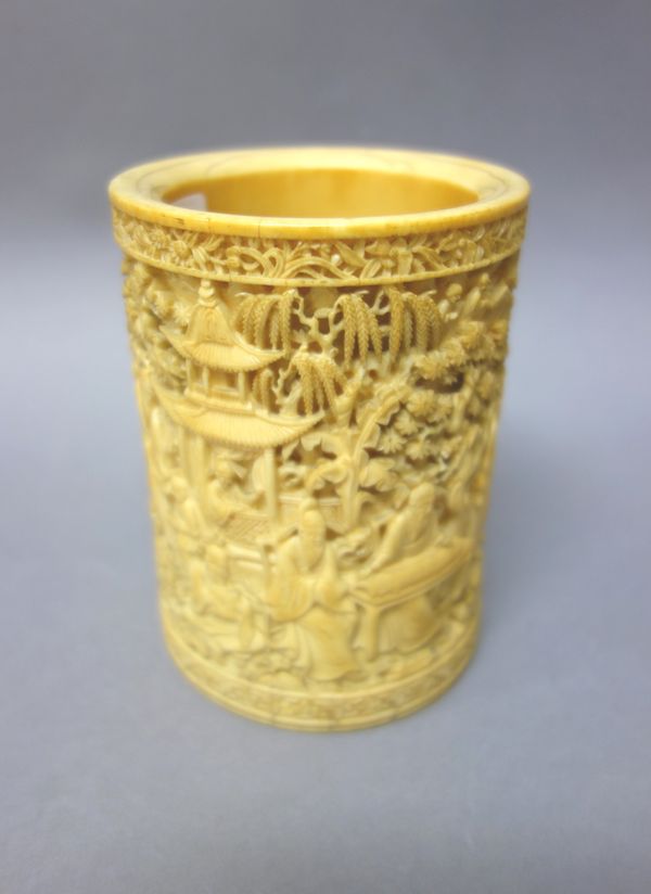 A Chinese ivory brush pot, late 19th century, of cylindrical form, profusely carved with scholars, pavilions, rocks and bamboo, (base plate lacking),