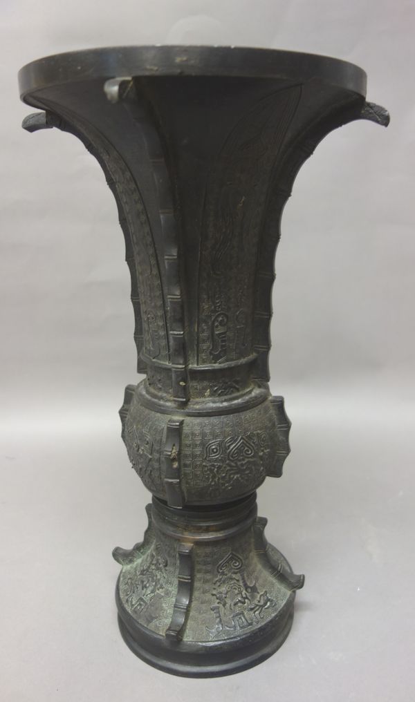 A tall Chinese bronze vase, probably 19th century, of Gu shape, cast with taotie masks and lappets against a leiwen ground, 44cm. high.