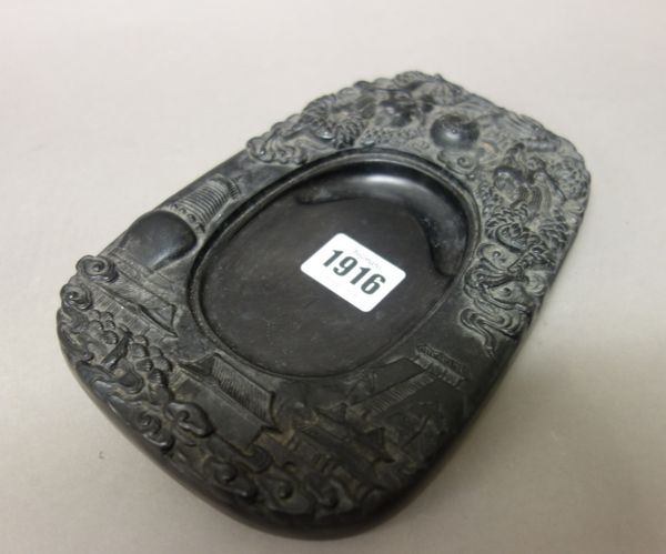 A Chinese inkstone and cover, the top part carved in relief with two dragons chasing a flaming pearl, above a stupa and pavilions in a landscape, the