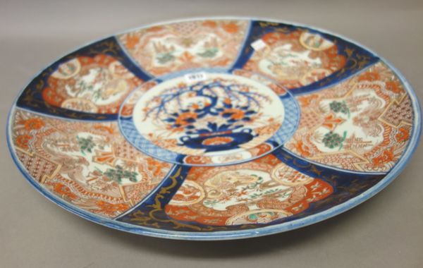 A Japanese Imari charger, Meiji period, painted with a central vase of flowers inside radiating panels enclosing minogame, pavilions and birds, 46.5cm