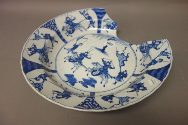 A large Chinese blue and white dish, Kangxi, painted in the centre with two warriors on horseback with attendants, beneath a border reserved with simi