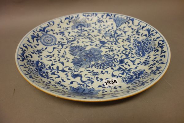 A Chinese blue and white dish, Kangxi, painted with lotus, chrysanthemum, peony and pomegranates, 36cm. diameter.