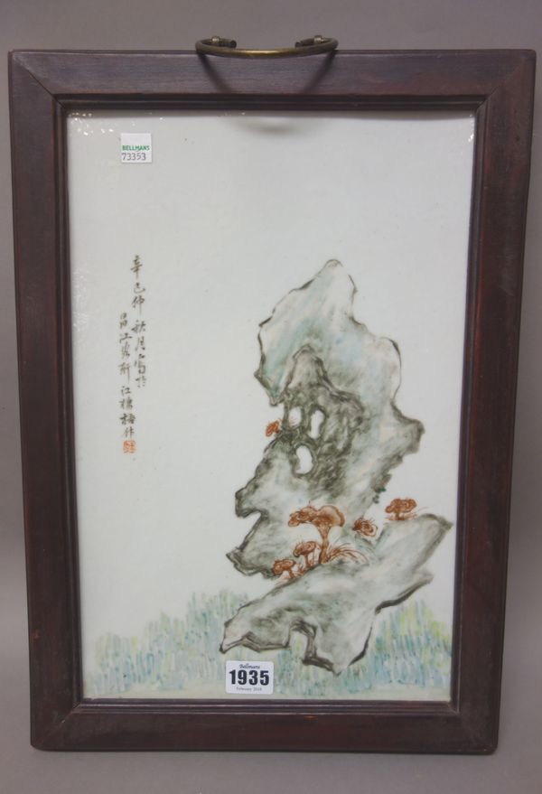 A Chinese porcelain rectangular plaque, 20th century, painted with fungus and greyish blue rocks beside calligraphy, 37cm. by 24cm., framed.